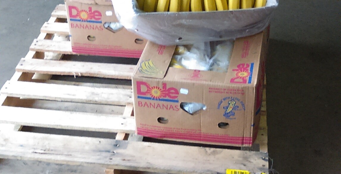 Boxes of bananas sitting on a pallet in a warehouse