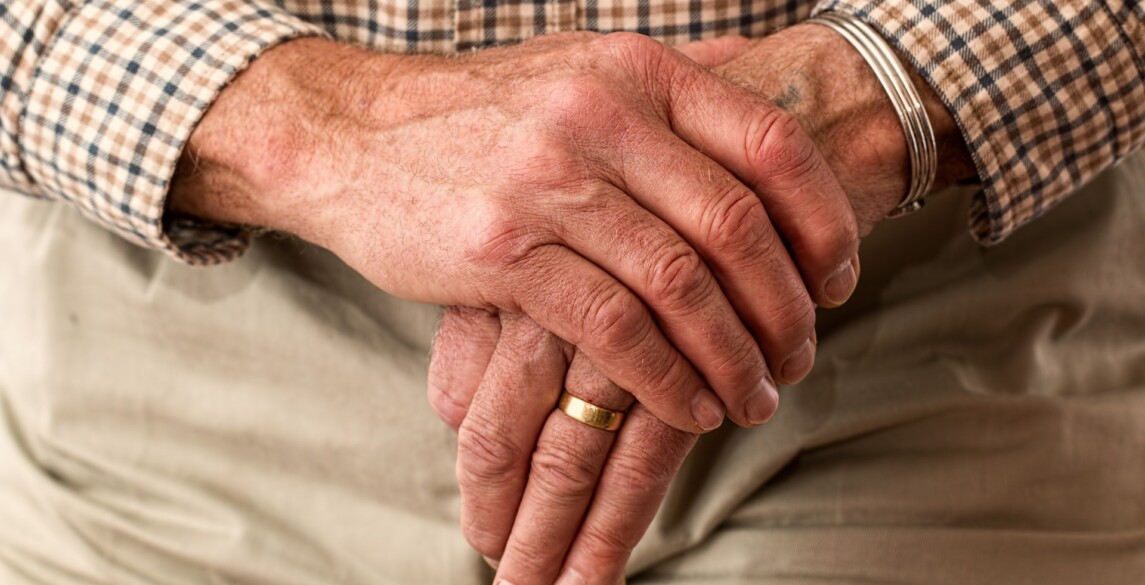 Older man's hands on a cane