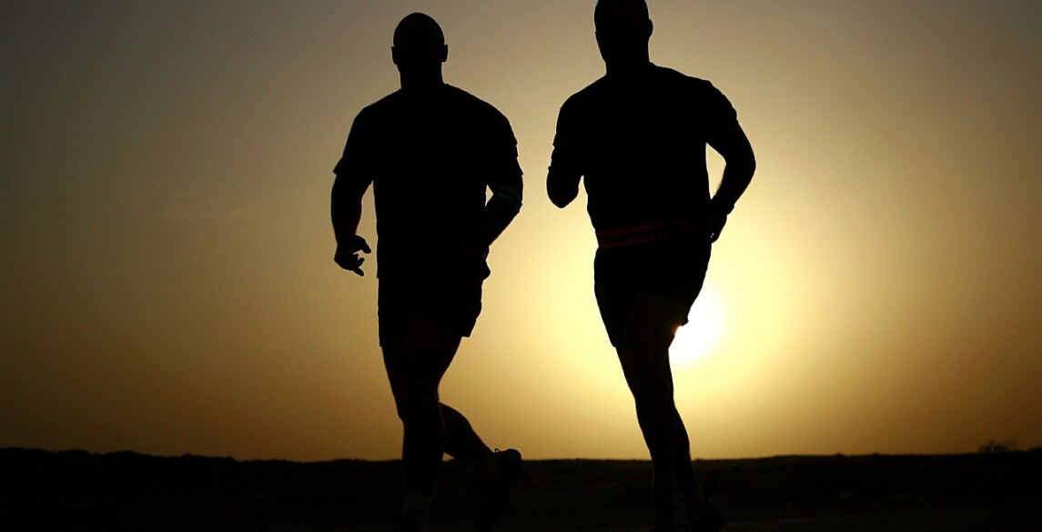 Two men running at sunrise