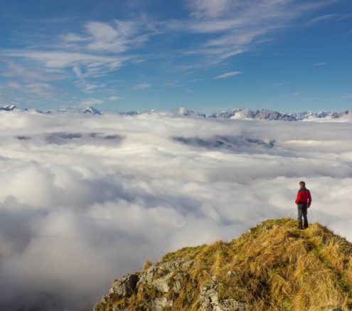 Man atop a mountain looking across landscape