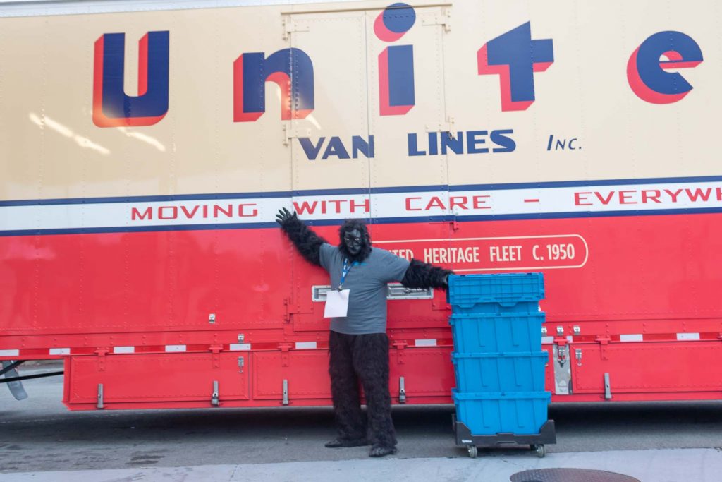 Tom Hinkley in gorilla suit posing in fron of United Van Lines moving truck