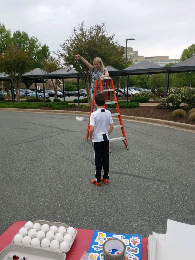 Hilldrup employees dropping an egg from the top of a ladder during a fun activity