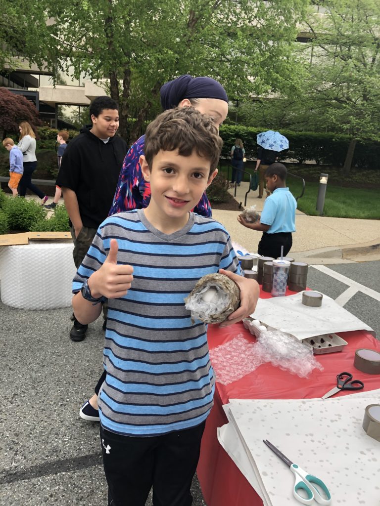 A boy holding his wrapped egg with a thumbs up
