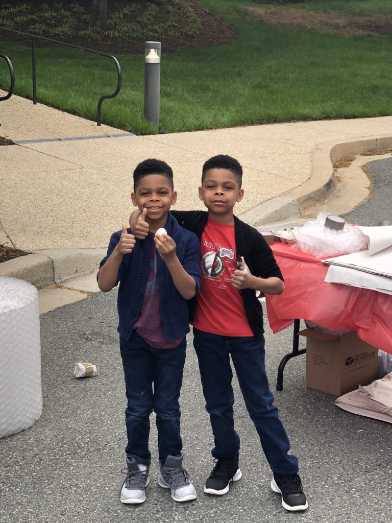 Two kids holding an egg with thumbs up