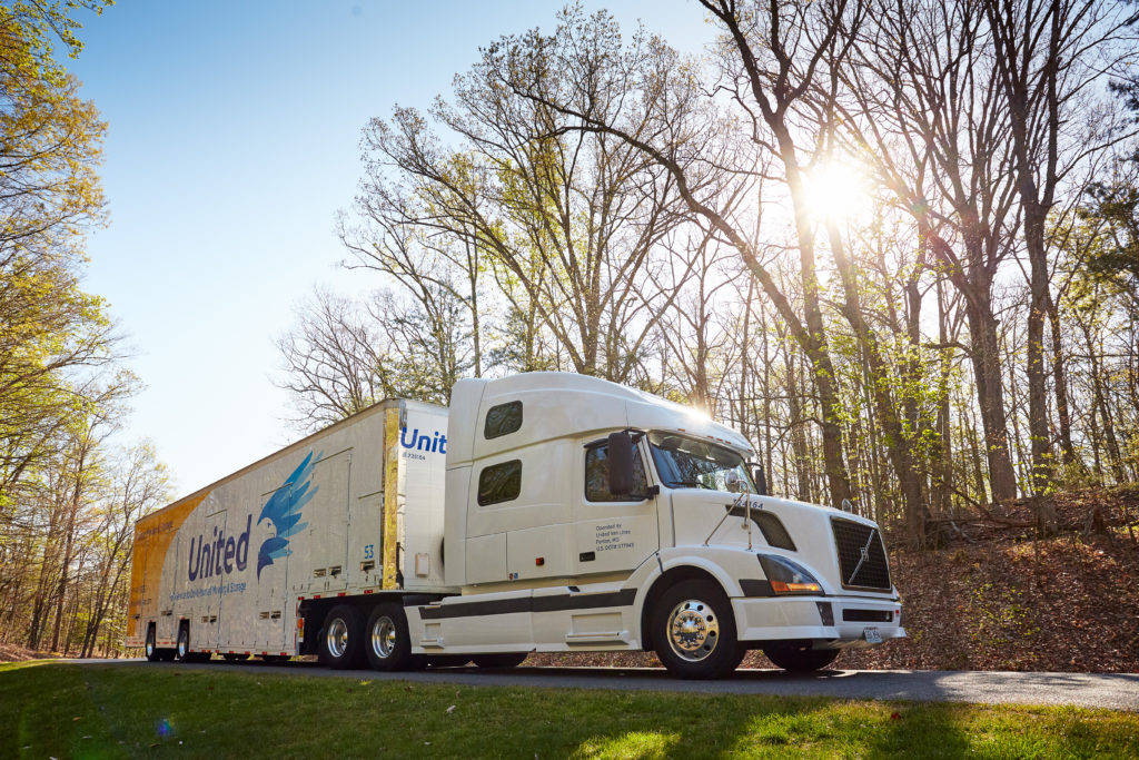 Hilldrup truck on the road with the sun peaking through the trees