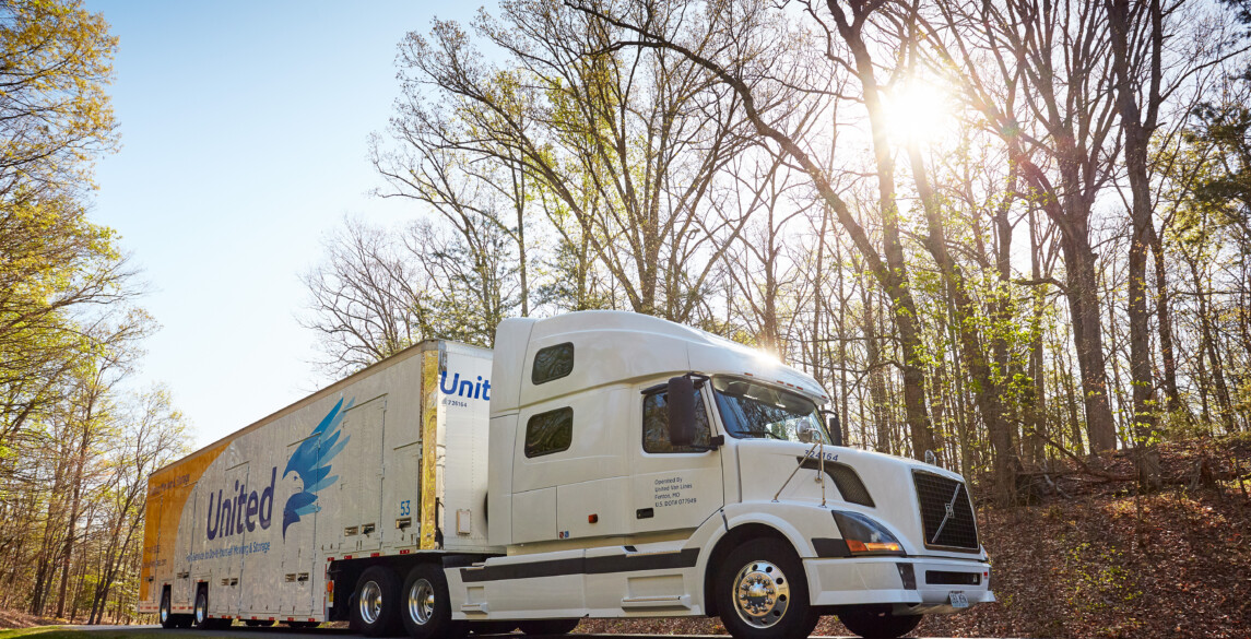 Hilldrup truck on the road with the sun peaking through the trees