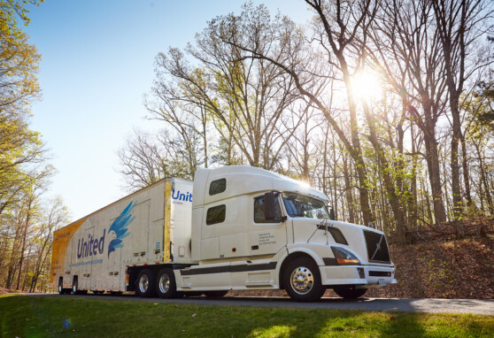 Hilldrup truck on the road with the sun peaking through the trees