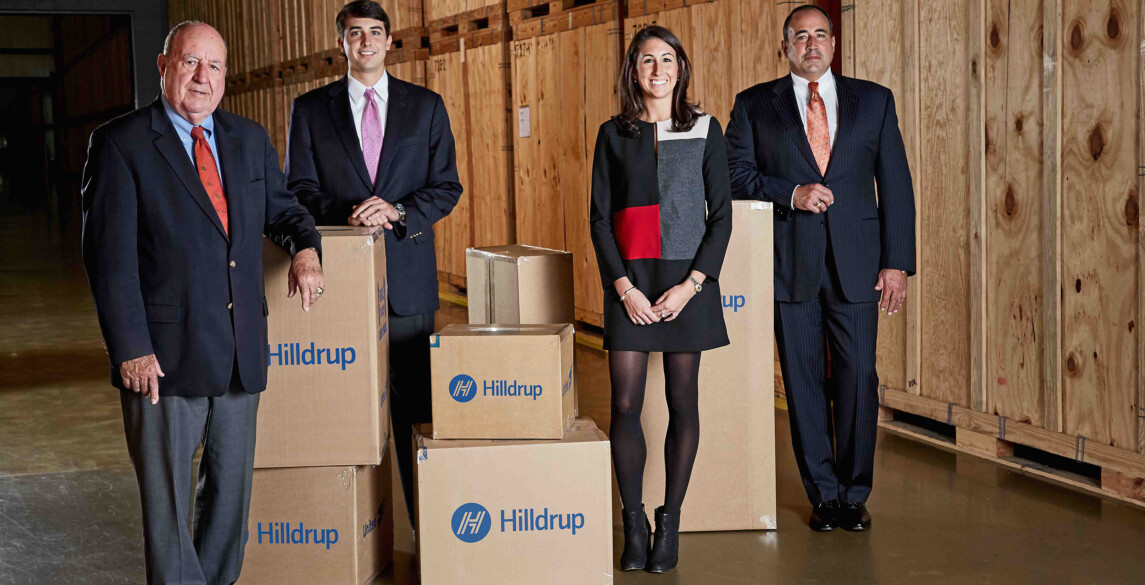 Charles G., Charlie, Jordan, and Charles W. McDaniel posing in a storage warehouse surrounded by moving boxes