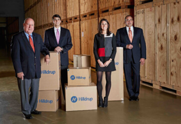 Charles G., Charlie, Jordan, and Charles W. McDaniel posing in a storage warehouse surrounded by moving boxes