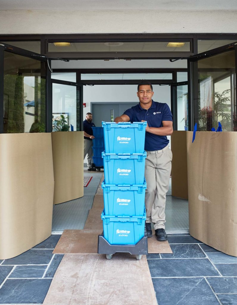 A Hilldrup employee with a stack of plastic bins