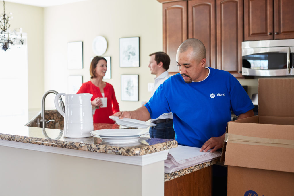 A Hilldrup packer packing dishes into a moving box