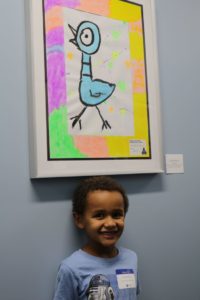 A young student poses with his artwork on display