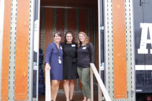 Three women pose at the entrance of one of Hilldrup's trucks during a tour