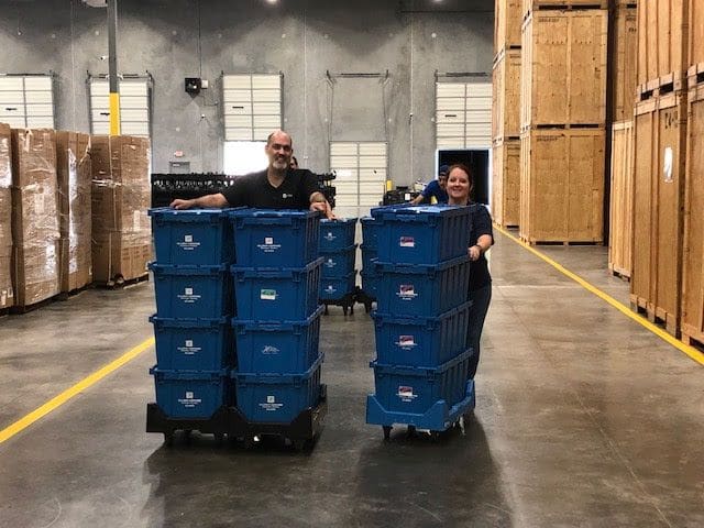 Two Hilldrup employees move crates across our warehouse.