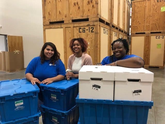 3 Hilldrup team members assist with moving items in Hilldrup's warehouse facility