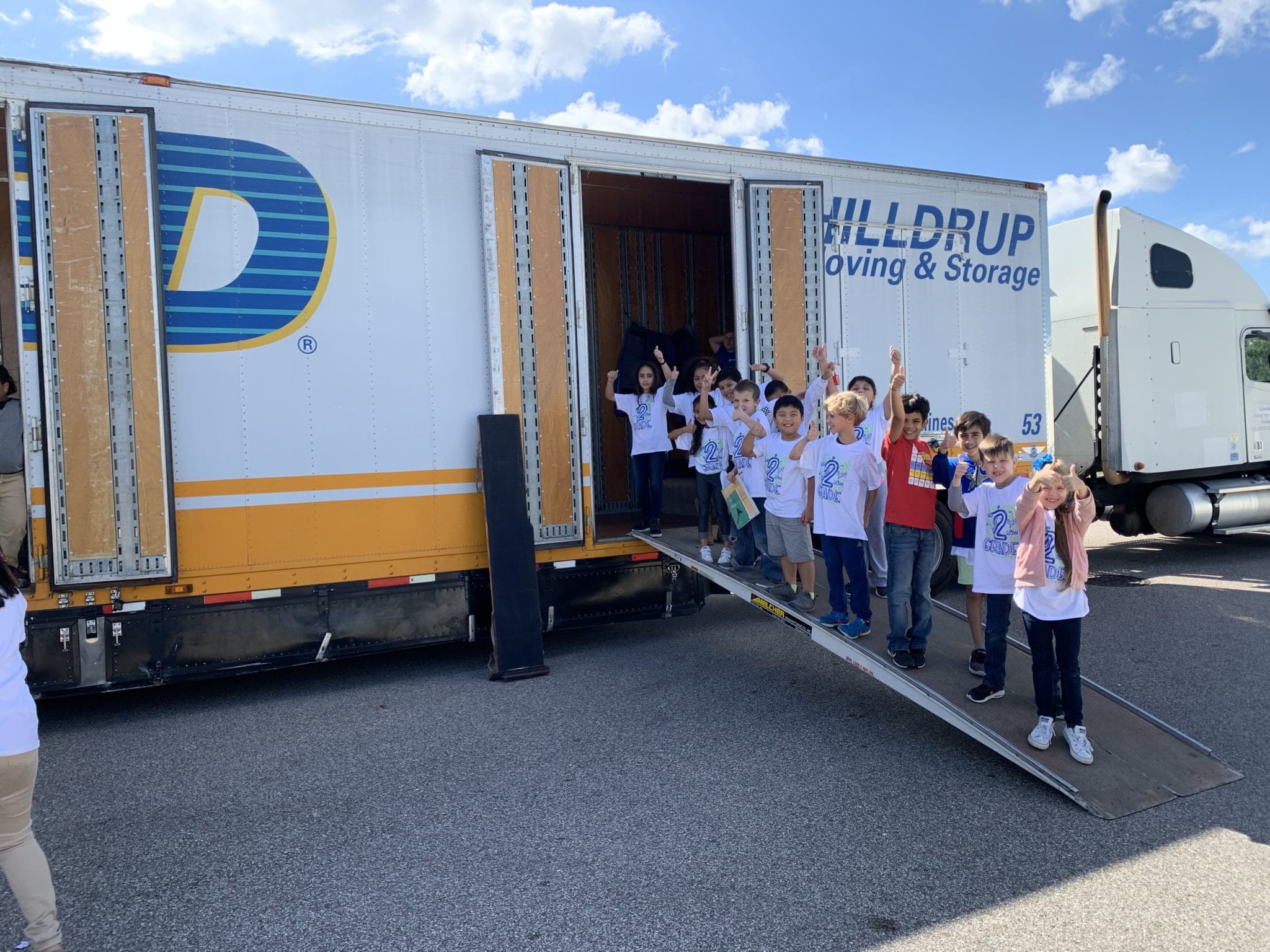 Hilldrup van operator talking to school children who are sitting down and learning about his tractor trailer