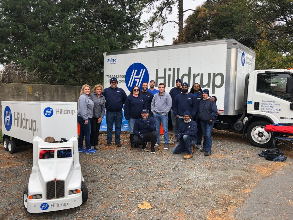 Hilldrup office employees and service team members gather for a photo next to a Hilldrup truck..