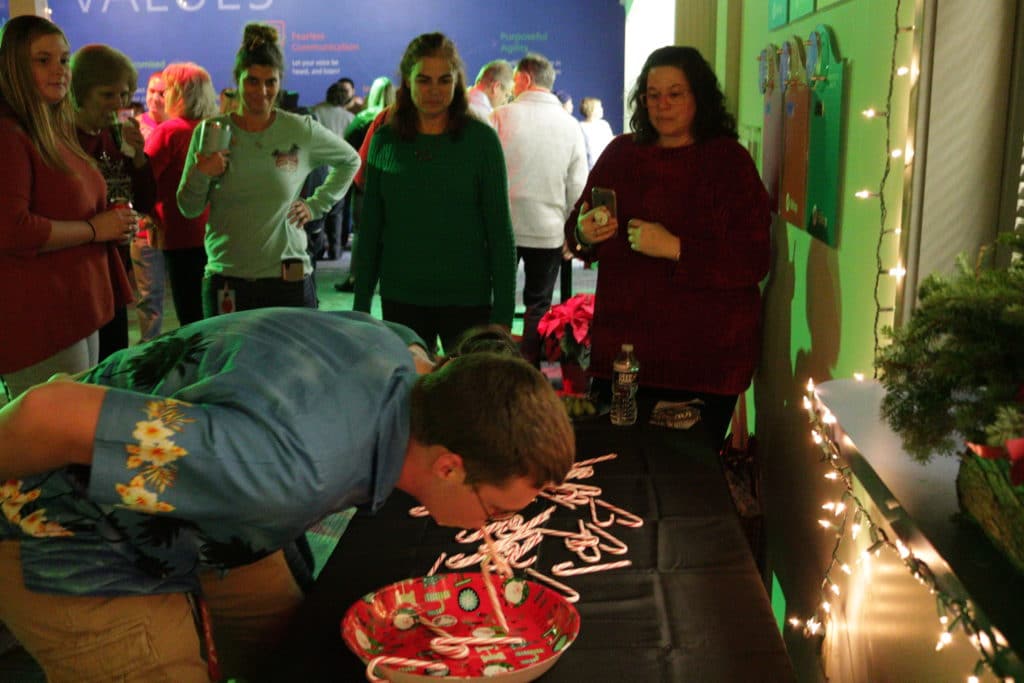 Hilldrup employee plays a Minute to Win It game with candy canes during Christmas party. 