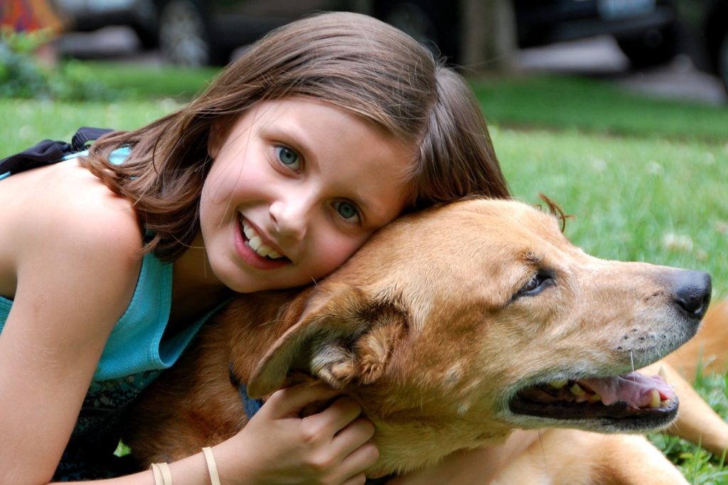 Young girl embracing pet dog.