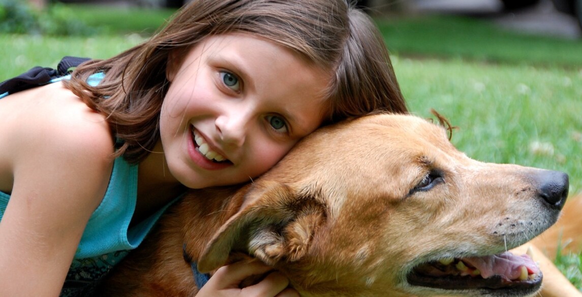 Young girl embracing pet dog.