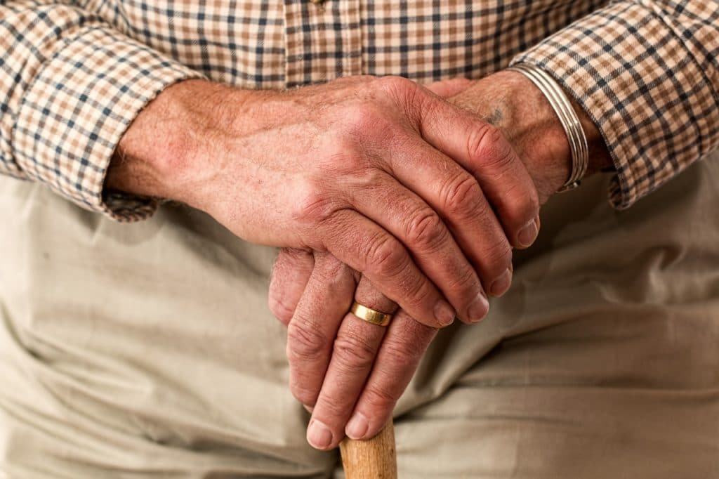 Elderly man's hands holding a cane.