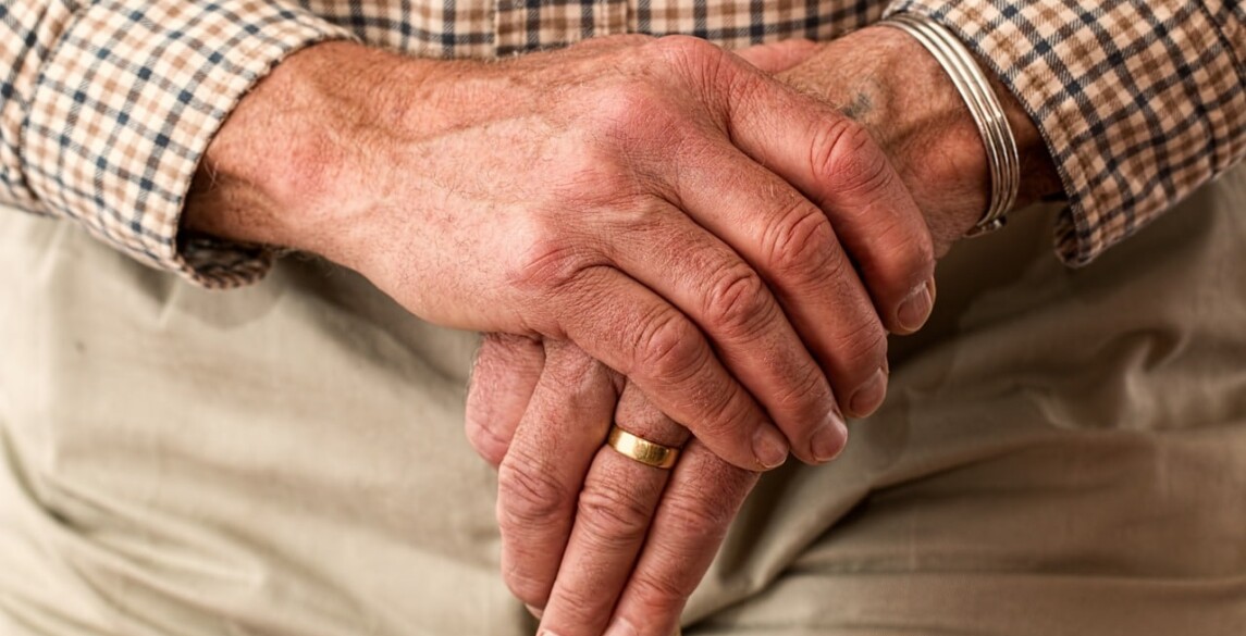 Elderly man's hands holding a cane.