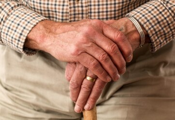 Elderly man's hands holding a cane.
