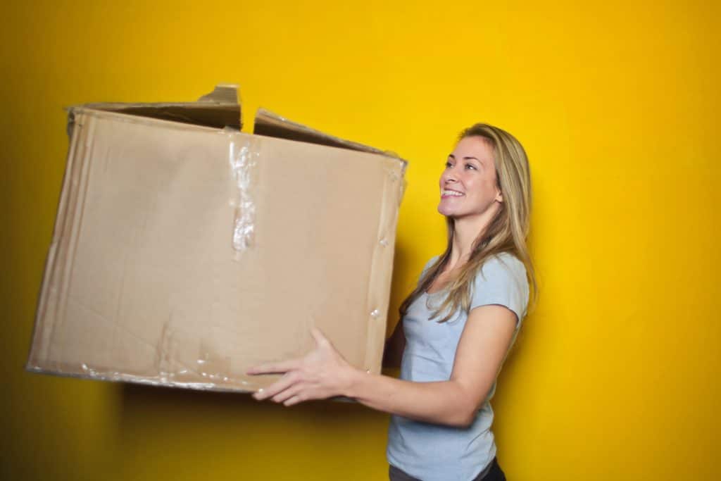 Young woman holding a moving box.|Young woman holding moving box.