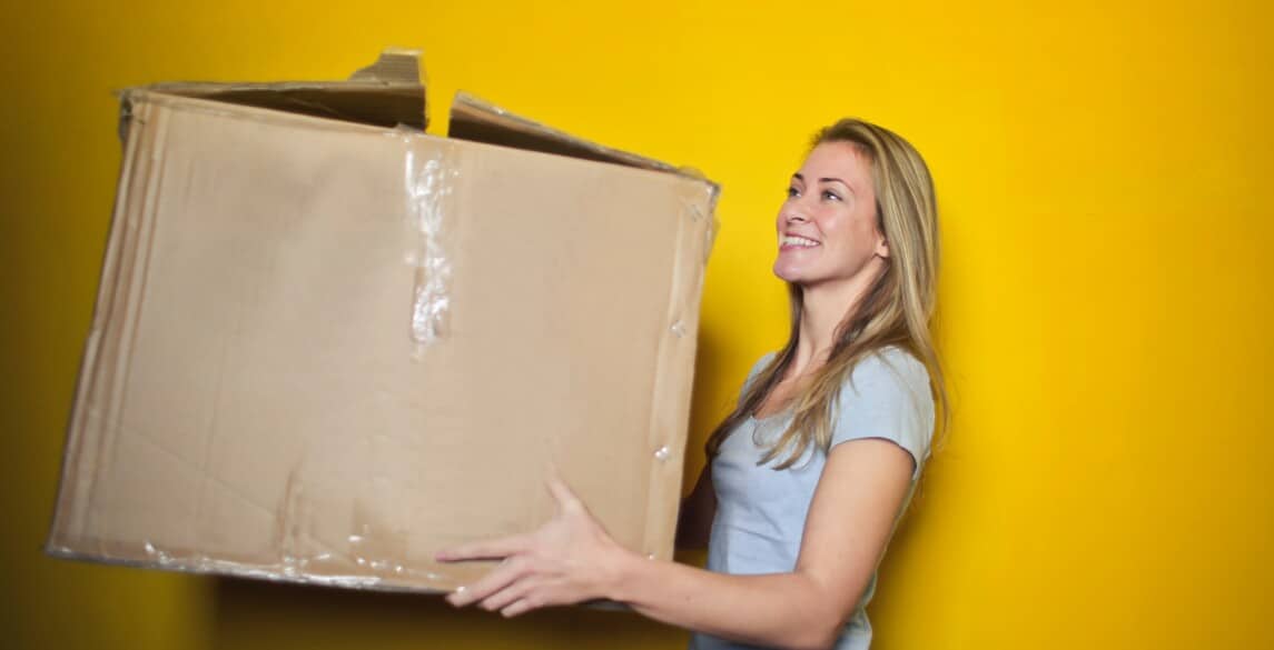 Young woman holding a moving box.|Young woman holding moving box.