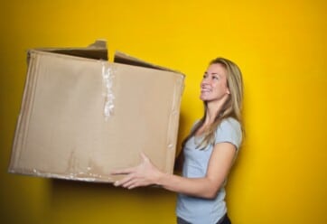 Young woman holding a moving box.|Young woman holding moving box.