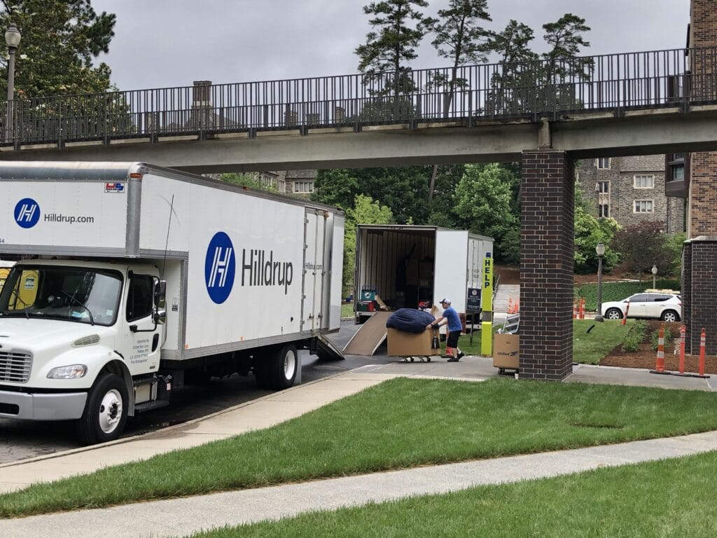 Man moving a box filled with packing supplies to a Hilldrup truck