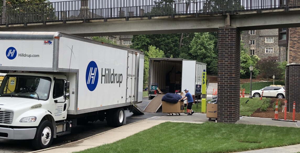 Man moving a box filled with packing supplies to a Hilldrup truck