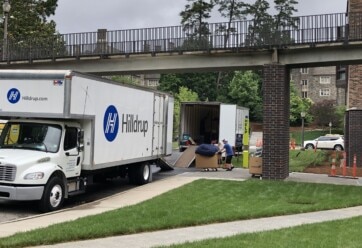 Man moving a box filled with packing supplies to a Hilldrup truck