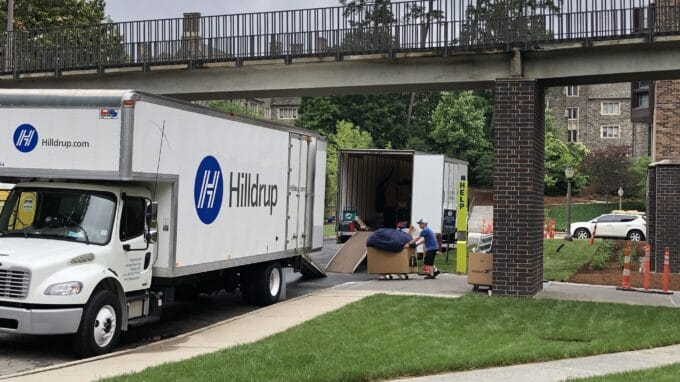 Man moving a box filled with packing supplies to a Hilldrup truck