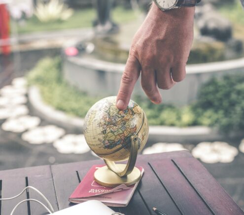 Person touching small globe on top of a passport.