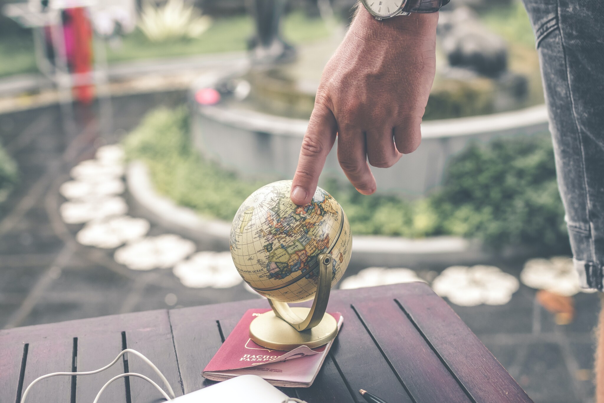 Person touching small globe on top of a passport.