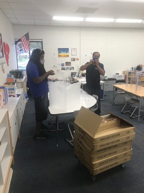 Hilldrup Charlotte's team assists with installing plexiglass shields in a classroom. 