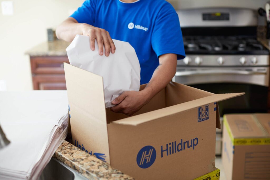 Hilldrup employee packing wrapped items in a kitchen.