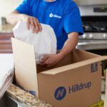 Hilldrup employee packing wrapped items in a kitchen.