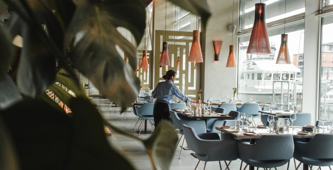 Picture of a restaurant with empty tables and a waitress.