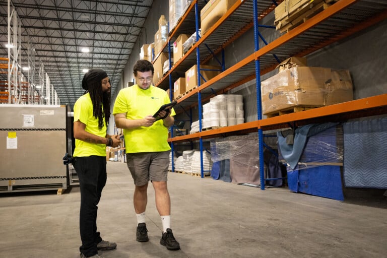 two men in warehouse looking at inventory on iPad