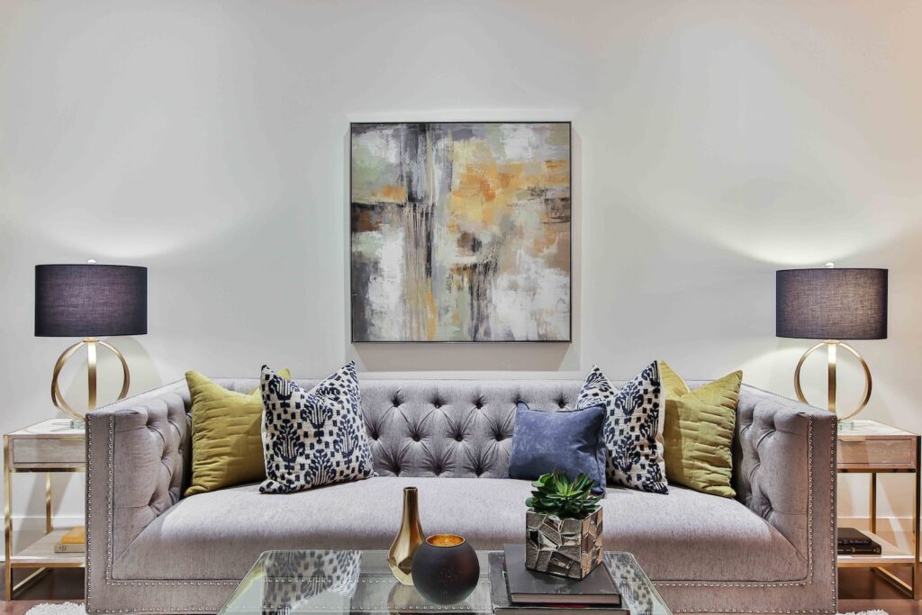 Picture of a living room with a couch, coffee table, side tables, lamps and a painting.