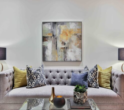 Picture of a living room with a couch, coffee table, side tables, lamps and a painting.