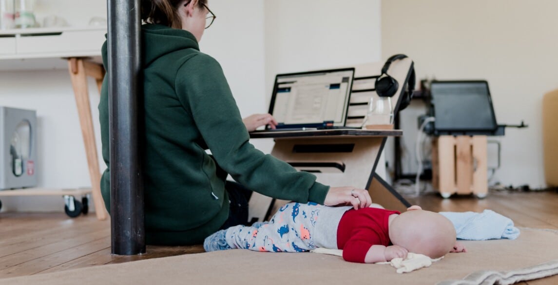 Woman working from home and taking care of her infant.