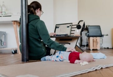 Woman working from home and taking care of her infant.
