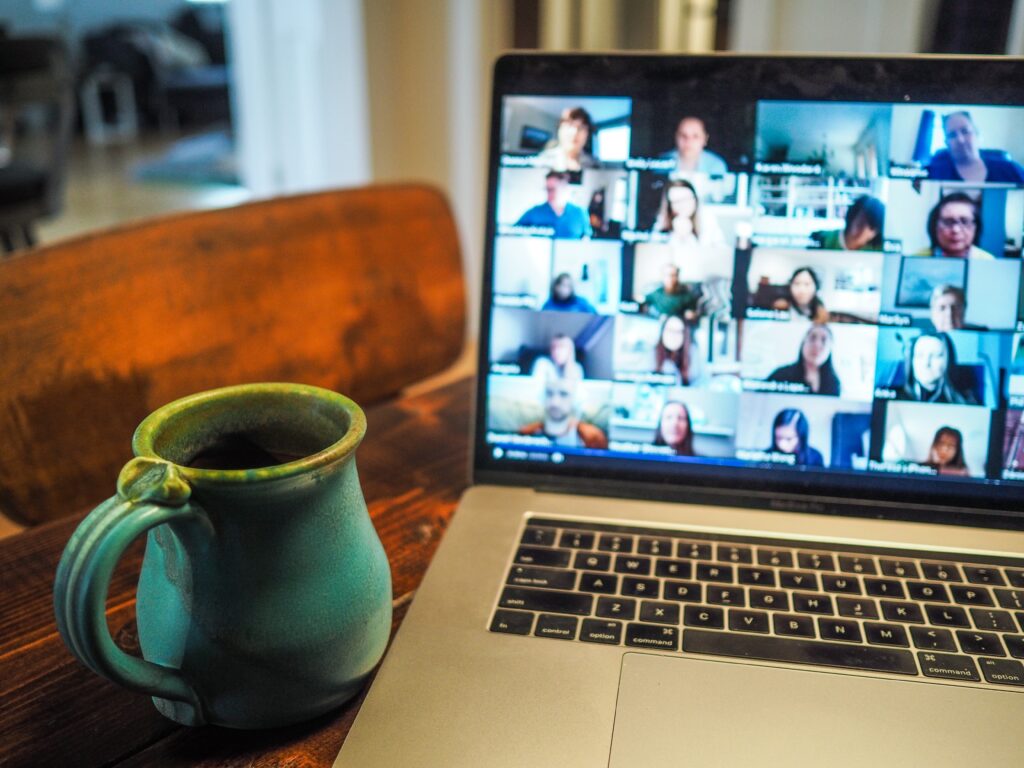 Picture of a desk with a coffee mug and a laptop with a Zoom screen up.