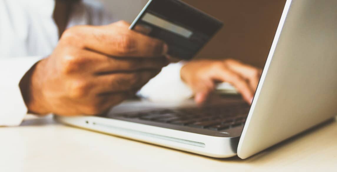 Person entering credit card information into a laptop.