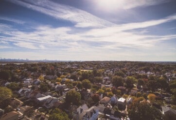 Overhead shot of neighborhood with blue sky and clouds in the background.