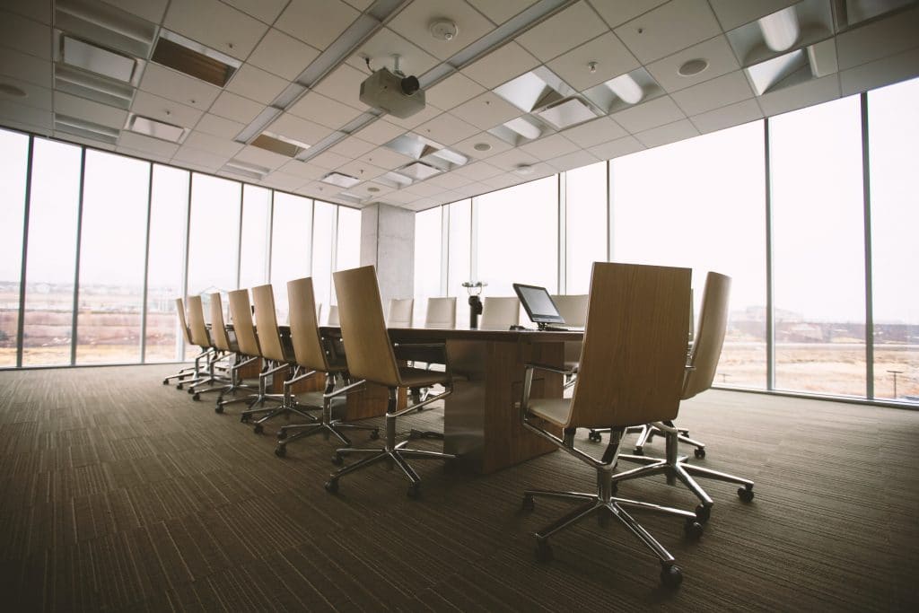 Conference room with a large table and chairs against a wall of windows.