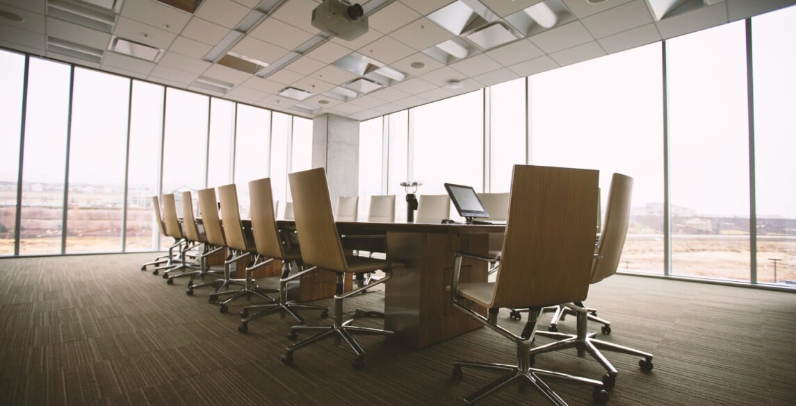 Conference room with a large table and chairs against a wall of windows.